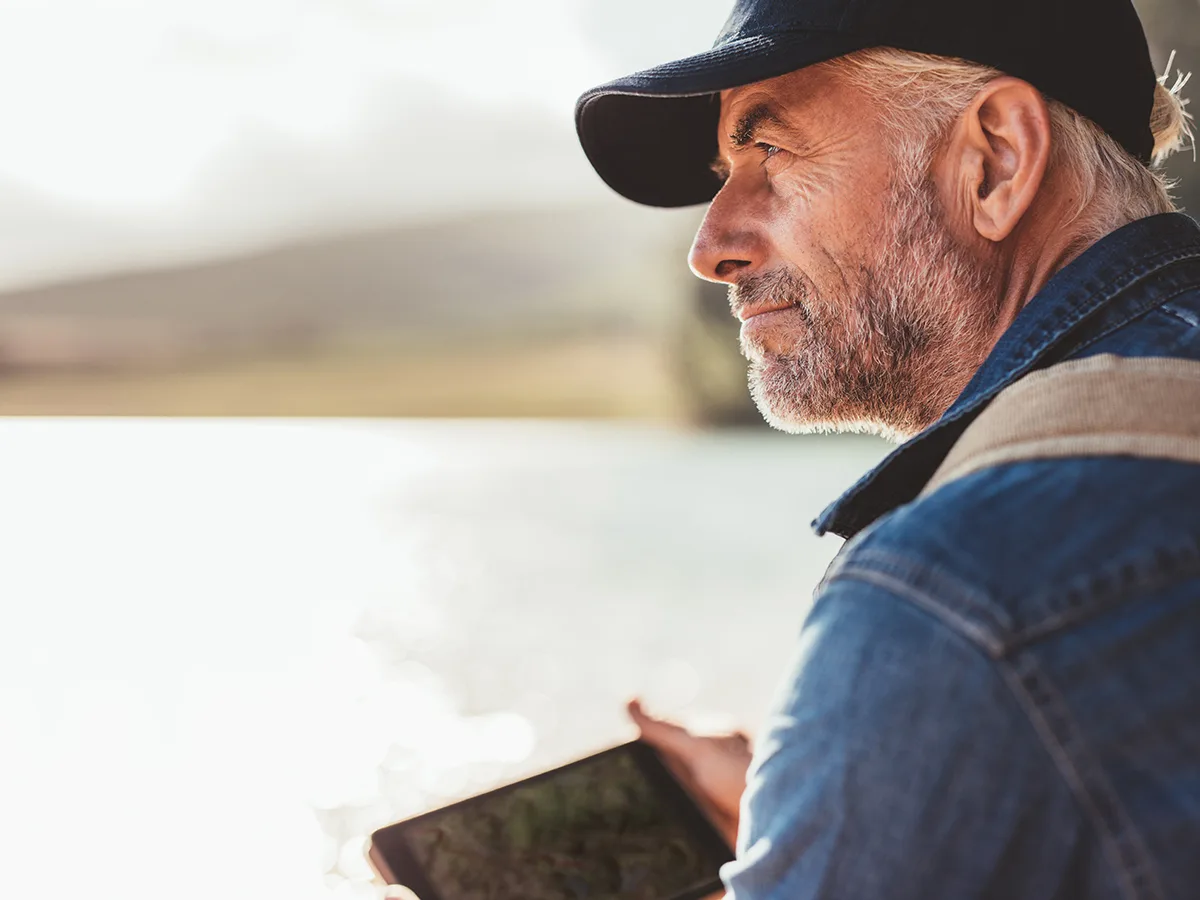 A man looking over water while holding an ipad