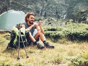 A man camping in the wilderness using his phone